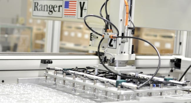 robot strips thermoformed electronics tray from plastic web